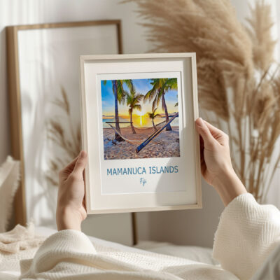 Person holds framed Mamanuca Islands sunset photo.